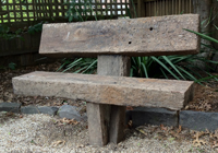 A solid red gum timber garden seat anchored into the ground